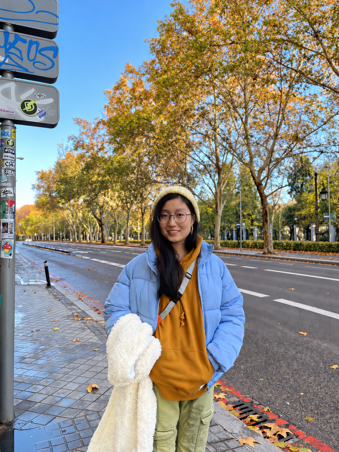 Keyan standing on an autumn tree-lined street in a blue jacket