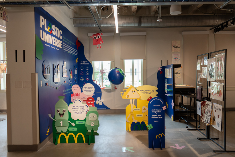 Plastic Universe exhibition with colorful plastic characters, a blue story wall, and an interactive globe